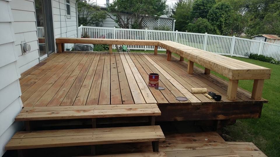 Spacious wooden deck with built-in benches, white railing, and manicured lawn in background