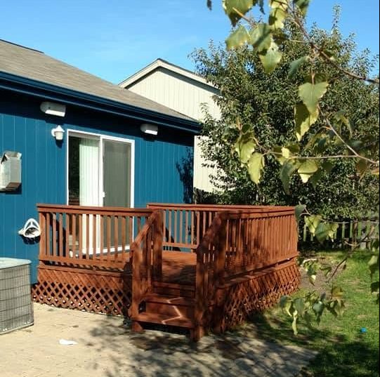 Red wooden deck with white railings attached to blue house with white trim