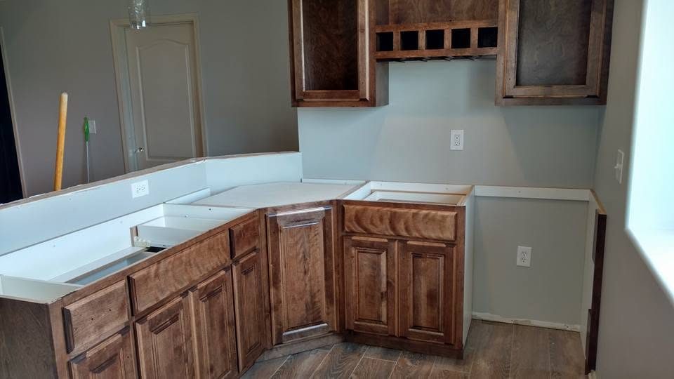 Kitchen renovation in progress with wooden cabinetry and white countertop installation