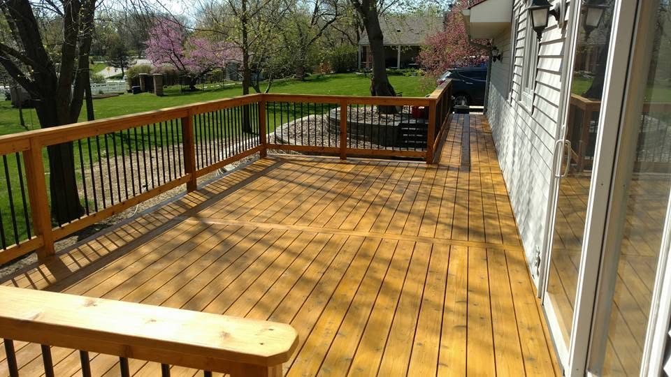 Spacious wooden deck with metal railing overlooking manicured lawn and blooming trees