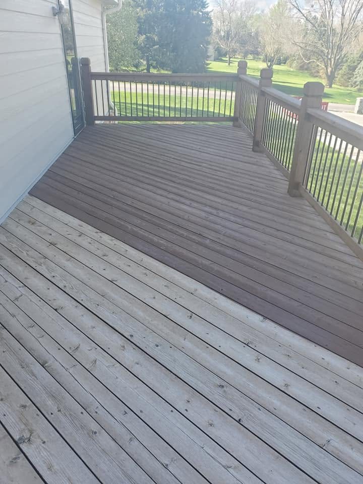 Deck with freshly stained boards transitioning from light to dark gray, metal railing, overlooking grassy yard