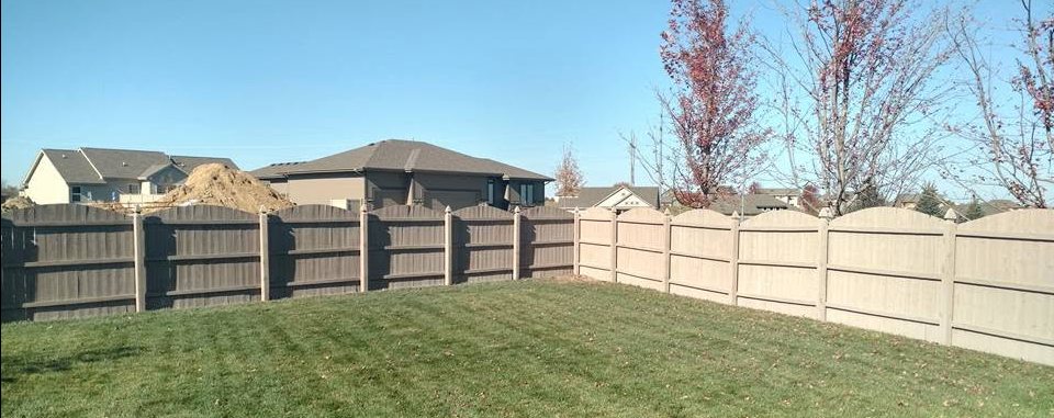 Residential backyard showing composite fence panels with horizontal boards in varying heights and colors