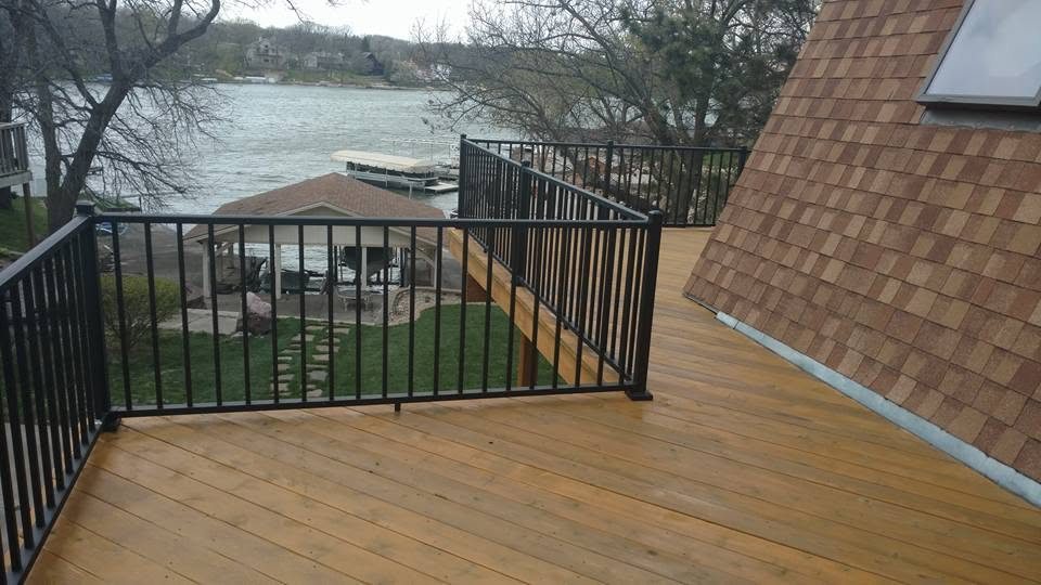 Waterfront deck with black metal railings and wooden decking overlooking a lake