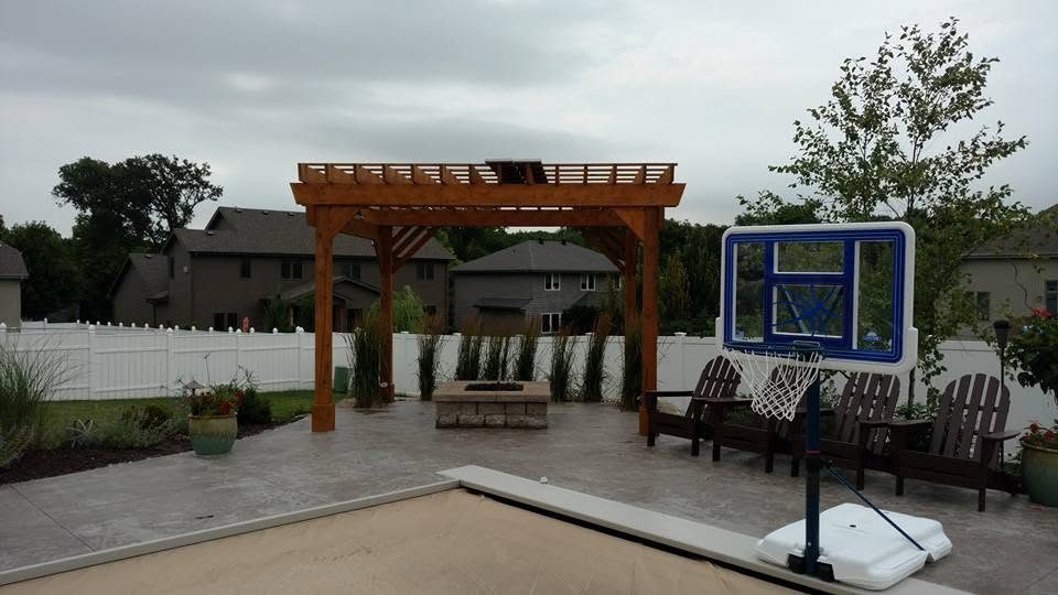 Backyard patio with wooden pergola, fire pit, basketball hoop, and Adirondack chairs