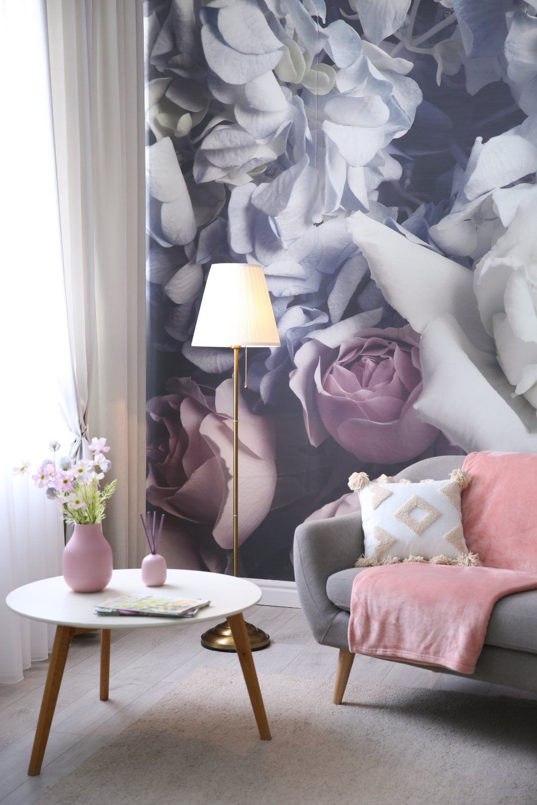 Modern living room with gray armchair, white side table, floor lamp, and large floral wall mural in pink and white tones